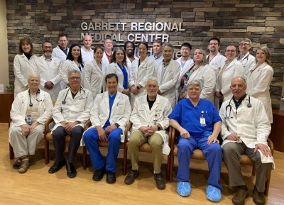 Physicians sitting and standing in front of the Garrett Regional Medical Center sign